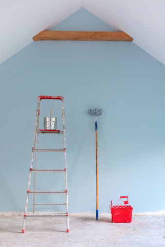 Paint tools with ladder against a newly painted light blue  wall