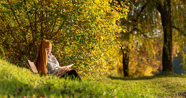 istock Woman read the book in autumn forest 451082213