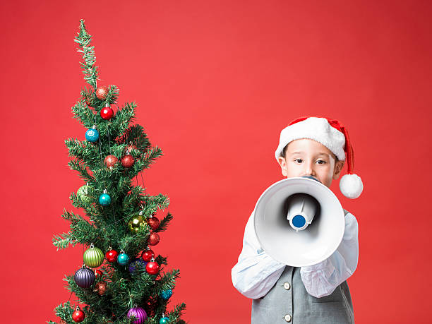 istock Little boy with santa hat shouting on old fashioned megaphone 451147631