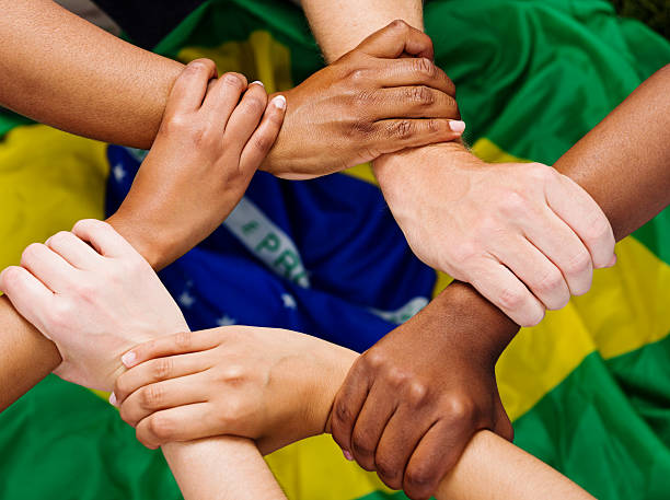 istock Six mixed hands clasped in unity against Brazilian flag 451148641