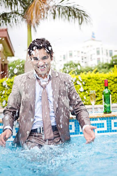 Excited Indian Businessman inside the Swimming Pool splashing water Excited Indian Businessman inside the Swimming Pool splashing water (Some Motion Blur) soaked suit stock pictures, royalty-free photos & images