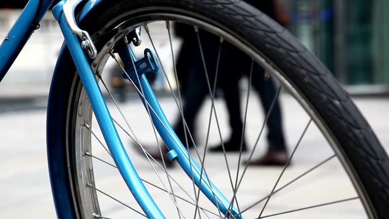 Padlocked city bicycle, pedestrians walking past. 2