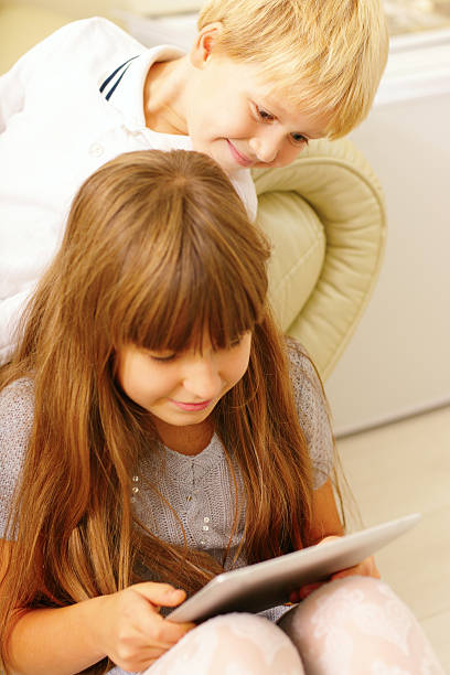 istock Brother and sister playing with tablet computer 451169193