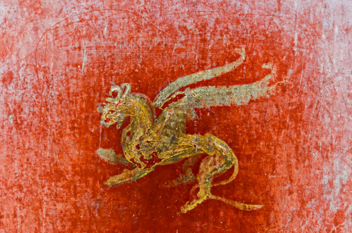 detail of the fresco in Pompeii with winged griffin on a red background Pompeian