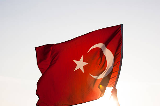 istock Hand waving the Turkish flag with sun on background 451173763