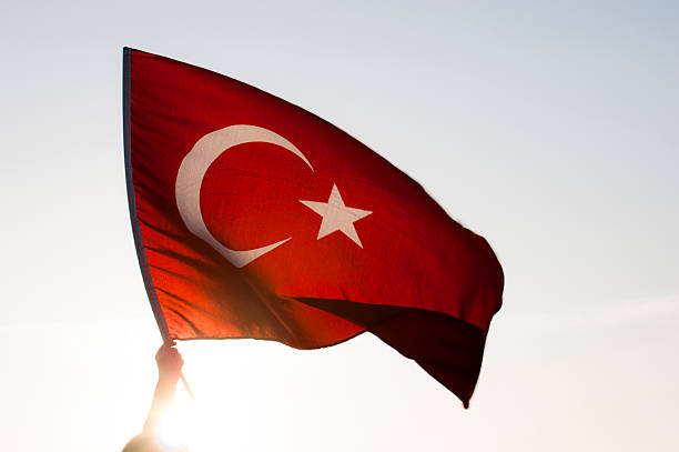 hand holding a turkish flag as it flies in the wind - türk bayrağı stok fotoğraflar ve resimler
