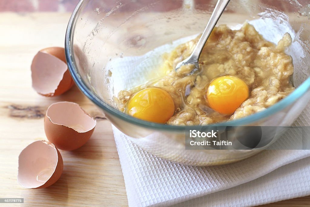 Mix of banana and eggs in a glass bowl Mix of banana and eggs in a glass bowl in process of making Banana cake with walnuts and dark chocolate Activity Stock Photo