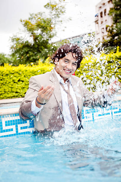 Excited Indian Businessman inside the Swimming Pool splashing water Excited Indian Businessman inside the Swimming Pool splashing water (Some Motion Blur) soaked suit stock pictures, royalty-free photos & images