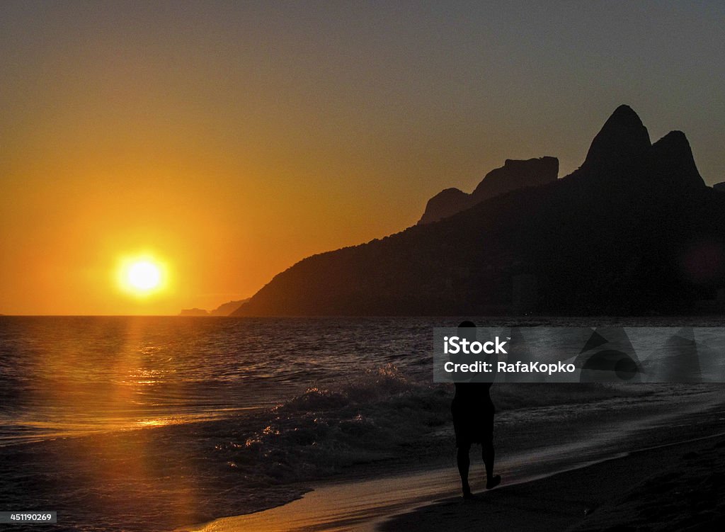 Men walking at the sunrise in Rio de Janeiro Men walking in the beach at the sunrise, Ipanema, Rio de Janeiro, Brazil Leblon Beach Stock Photo