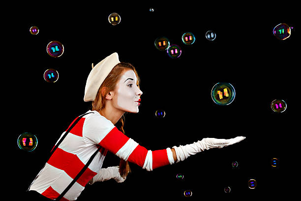 Female mime catching bubbles against black background