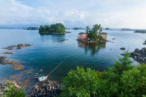 Beautiful calm summer, seascape with boat and houses on tiny forested islands in Sitka Sound on Baranof Island, Alaska
