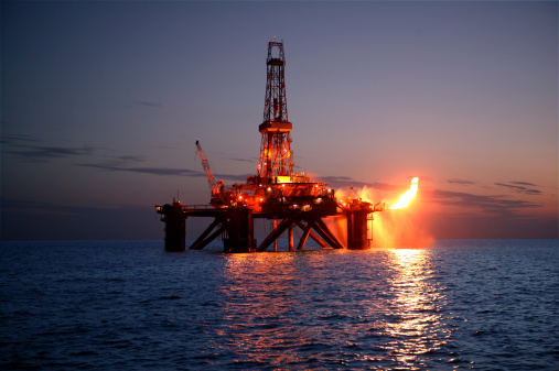 Offshore oil rig flaring in evening light.