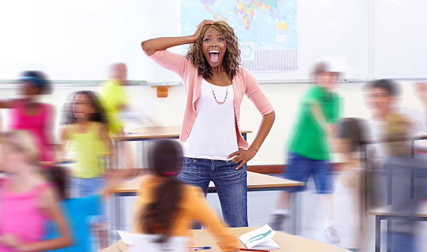 Chaos Portrait of a young teacher shouting as her students run around her irritation photos stock pictures, royalty-free photos & images