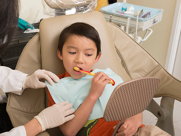 istock Young boy on dentist chair learning how to brush his teeth 451258421