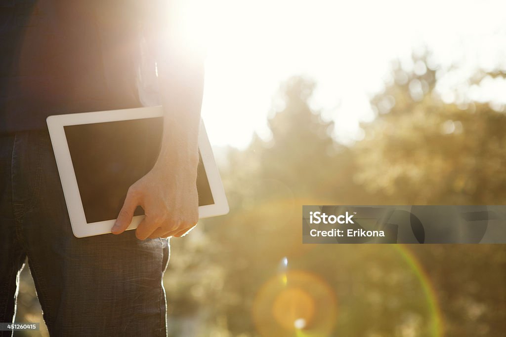 Man holds digital tablet Man holds digital tablet in sunset forest Adult Stock Photo