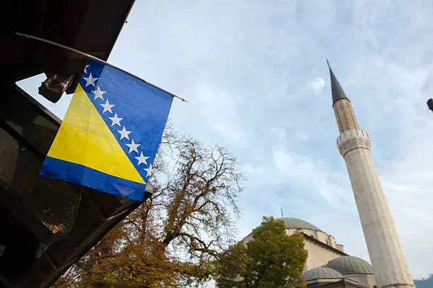 The national flag of Bosnia and Herzegovina hangs from a building across the street from the Gazi Husrev-beg Mosque in the old town of Sarajevo, Bosnia and Herzegovina. The mosque was completed in 1531.