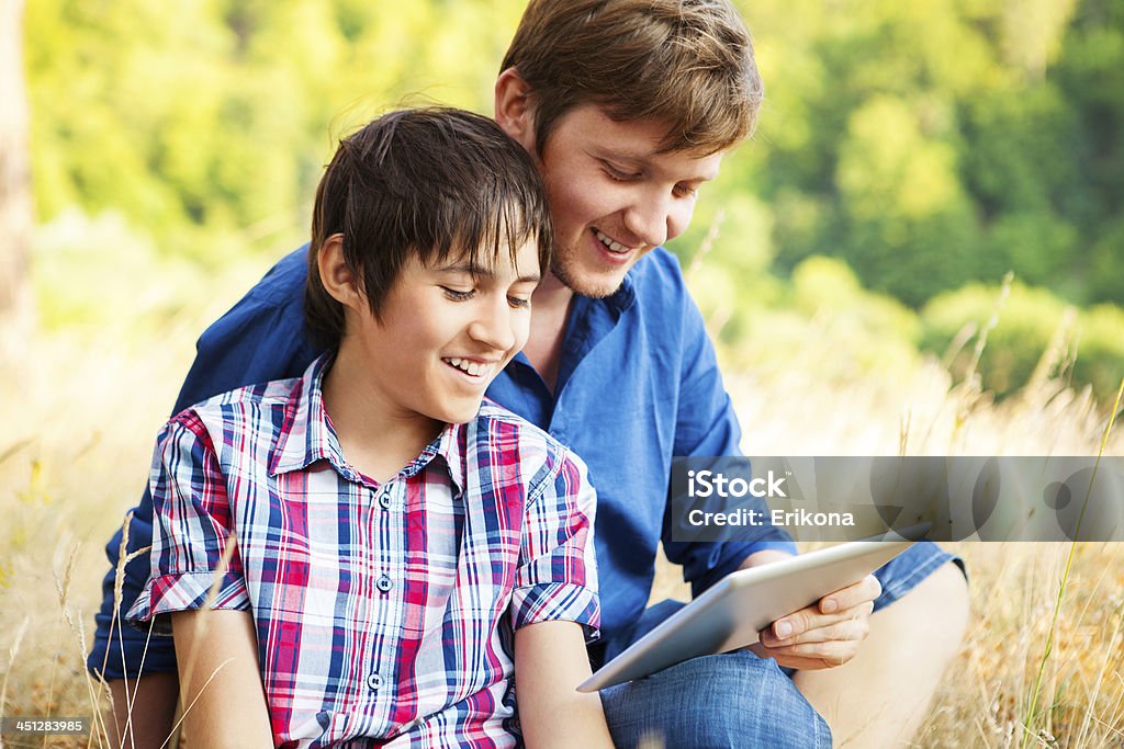 Man and boy using digital tablet Man and boy using digital tablet on sunset nature Adult Stock Photo