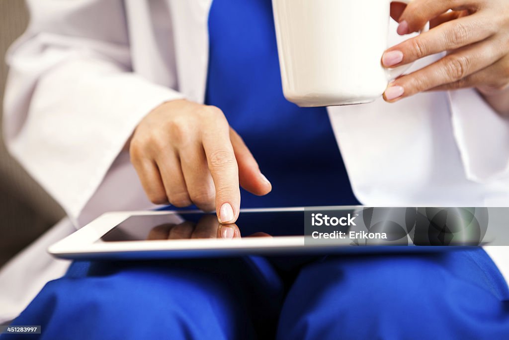 Doctor touching digital tablet Doctor touching screen digital tablet and drink coffee Personal Data Stock Photo