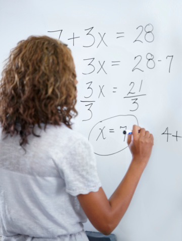 A young teacher doing maths equations on the whiteboard
