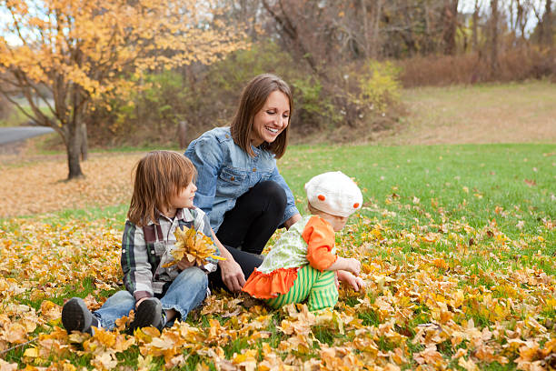 istock Mother And Children Gathering Fall Leaves 451300969