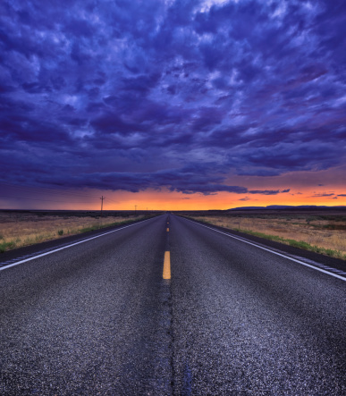 Asphalt road leading through Utah desert during sunset. Stitched composite image.