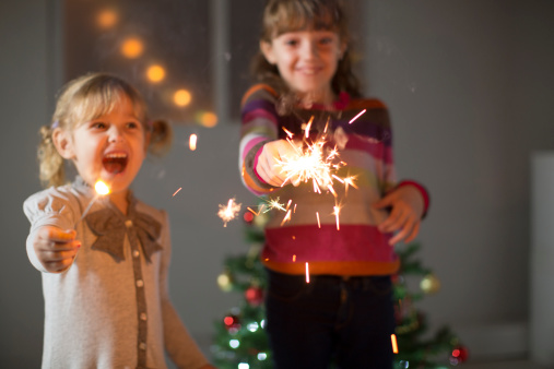 Happy children, two little girls, sisters having fun at home with Christmas Sparklers. Shallow DOF.