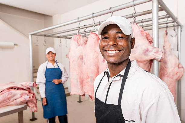 Workers at a slaughterhouse Portrait of two workers smiling and working at a slaughterhouse meat packing industry photos stock pictures, royalty-free photos & images
