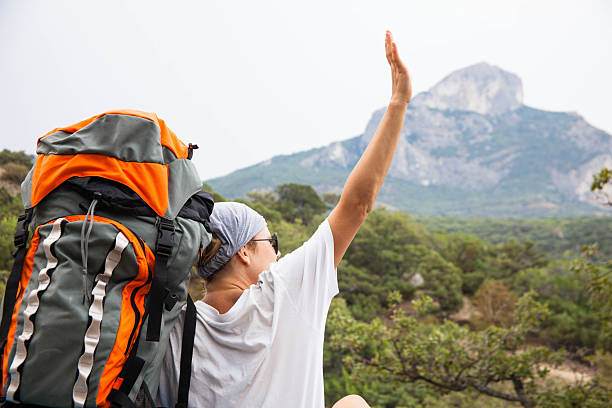 istock Young happy woman with backpack relaxing on a rock 451372245