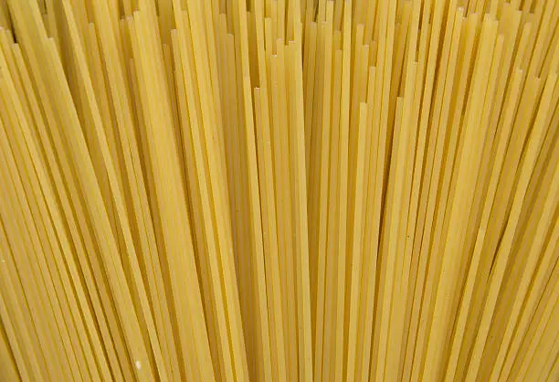 Bundle of long spaghetti on a old grungy wooden desk.