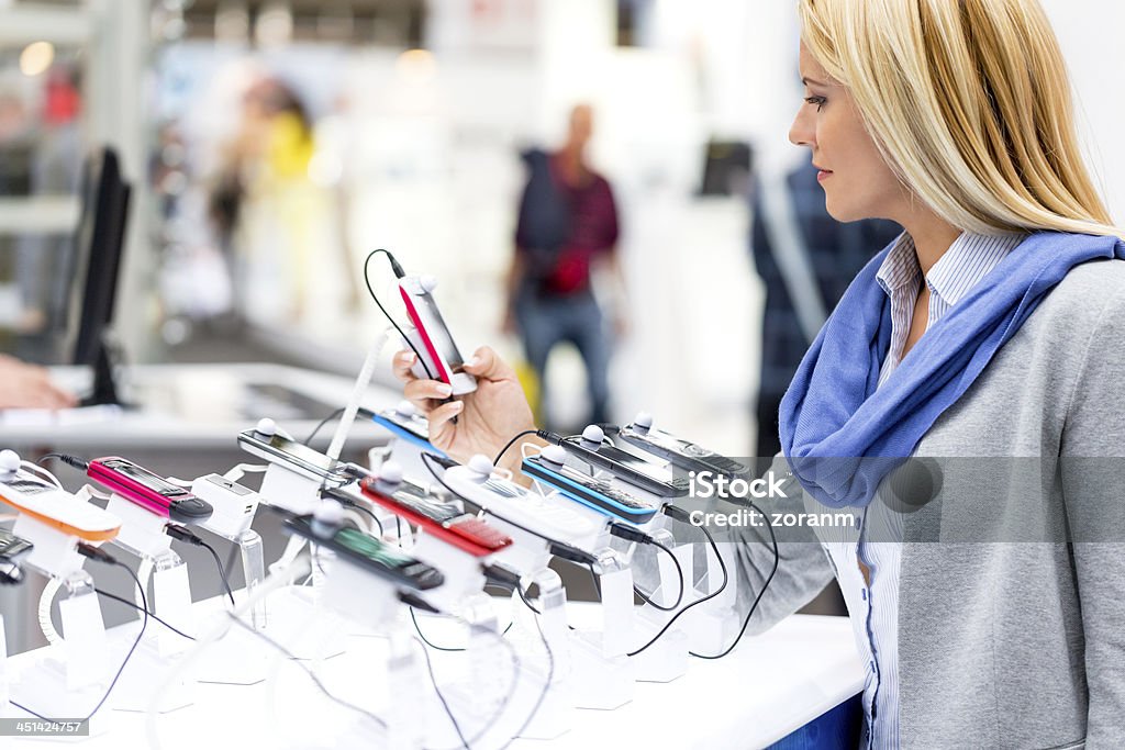 Blonden Frau auf der Suche auf smartphones im store - Lizenzfrei Elektrogeschäft Stock-Foto