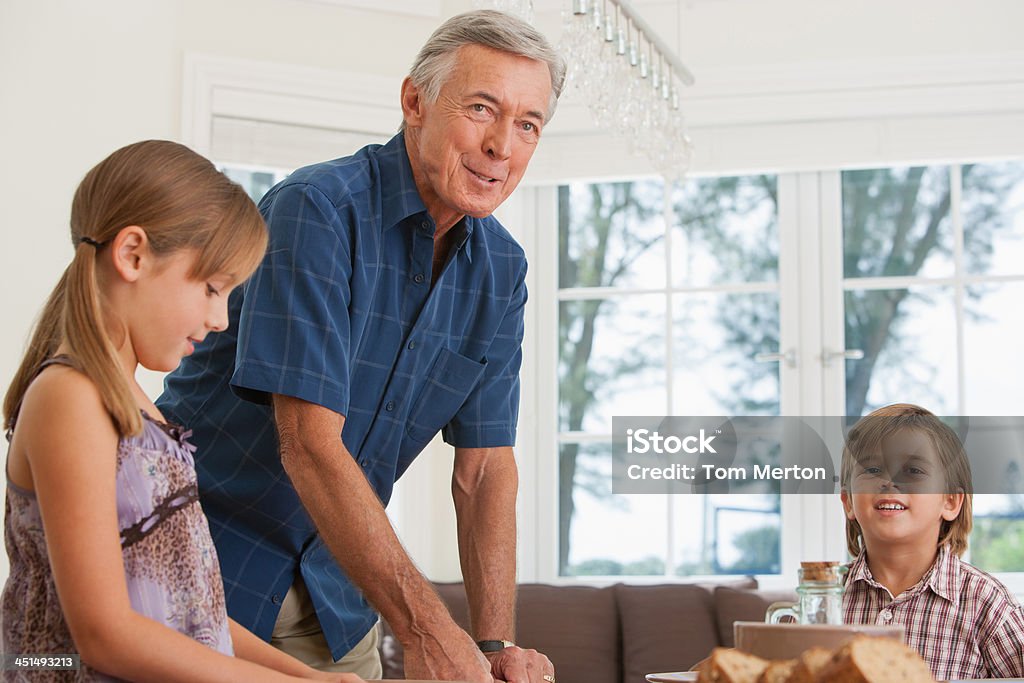 Homme et deux enfants à la table de salle à manger - Photo de Hommes seniors libre de droits