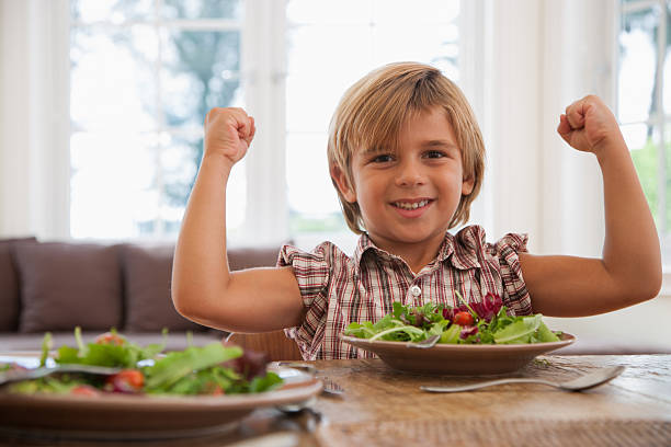 jeune garçon sur une table de salle à manger en fléchissant - child human muscle flexing muscles little boys photos et images de collection