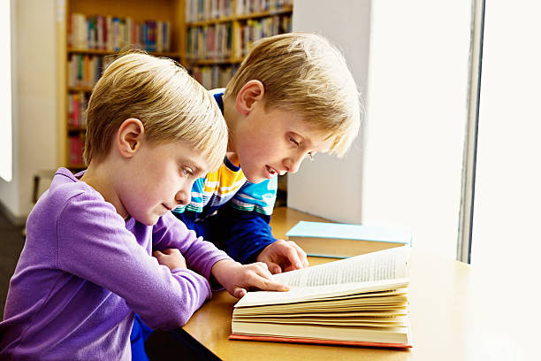 istock It just takes practise! Brother helping sister learn to read 451531145