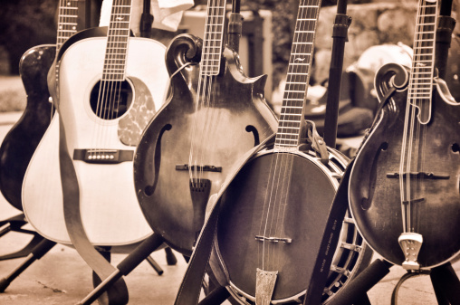 5 stringed instruments sit on a stage ready to be played.