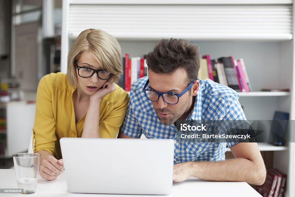 Two surprised students learning in library Two surprised students learning in library on laptop Adult Stock Photo