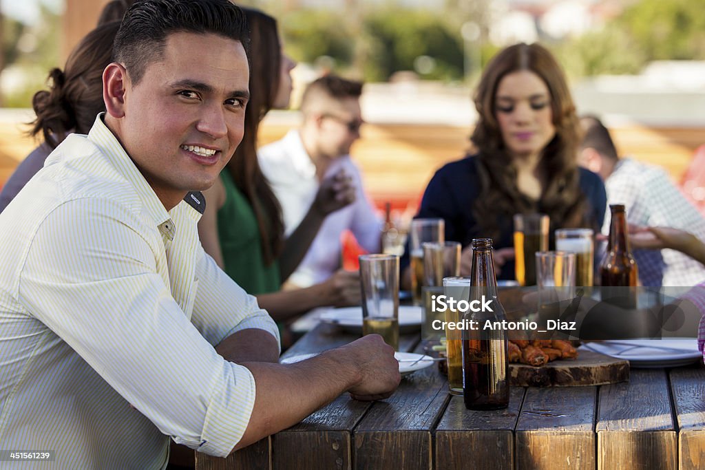 Handsome man with his friends Portrait of a young Hispanic man having snacks and beer with some of his friends at a bar 20-29 Years Stock Photo