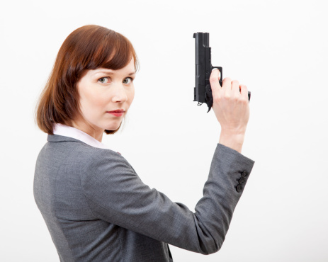 Portrait Of A Woman Holding Gun against a grey background