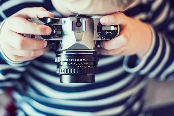 istock Boy is taking a photo with an old camera 451573485
