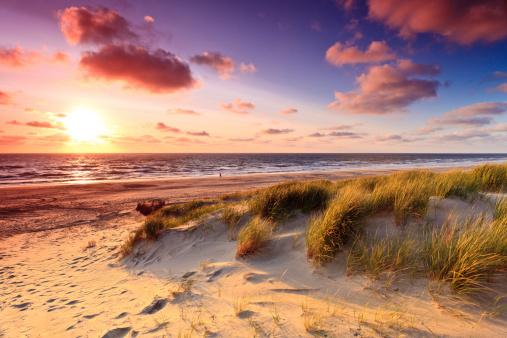 Seaside with sand dunes and colorfull sky at sunset