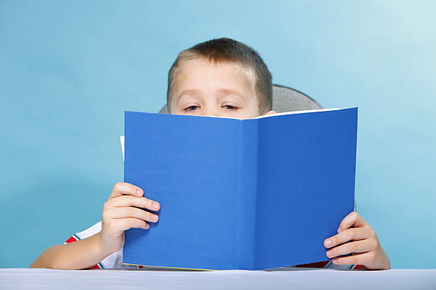 istock child boy kid reading a book on blue 451582451