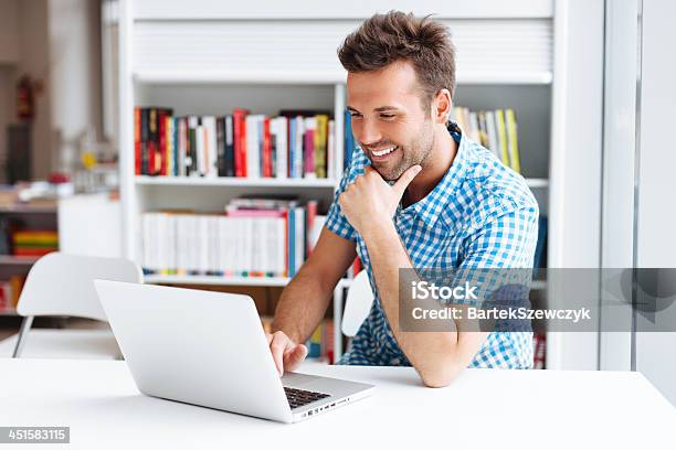 A Man Smiling While Facing His Laptop Stock Photo - Download Image Now - University Student, Lifestyles, Modern