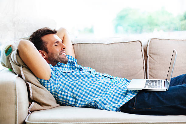 istock Man relaxing with laptop on couch 451583151