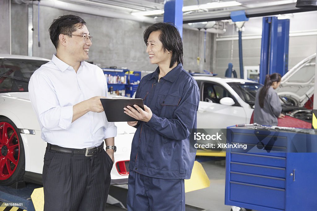 Businessman talking to Mechanic in Auto Repair Shop Beijing Stock Photo