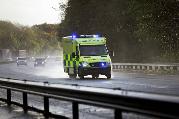 Ambulance British ambulance responding to an emergency in hazardous bad weather driving conditions on a UK motorway ambulance stock pictures, royalty-free photos & images