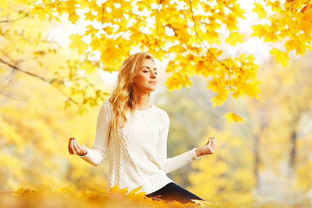 istock Woman meditating in autumn park 451601025