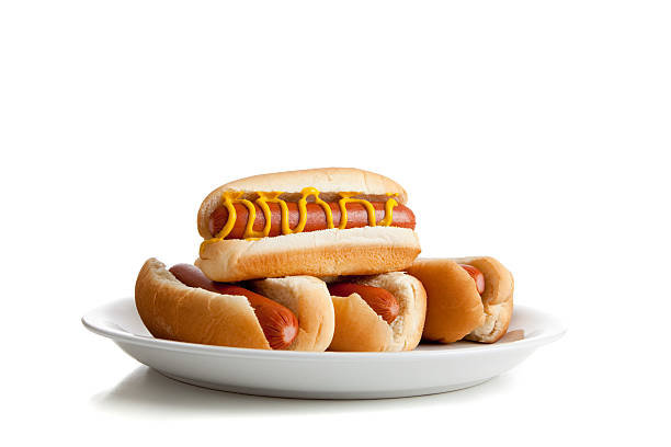 Stacked hot dogs with mustard and buns on white stock photo