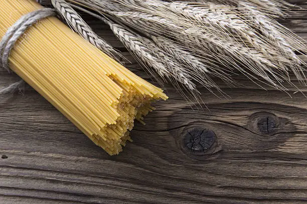 Bundle of long spaghetti on a old grungy wooden desk.