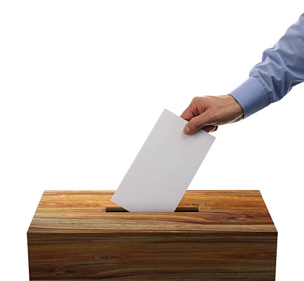Male placing his voting envelope into a wooden ballot box