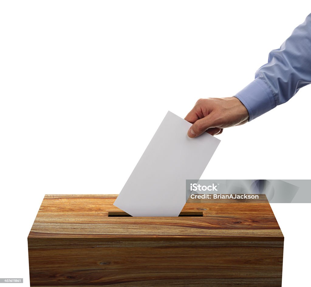 Male placing his voting envelope into a wooden ballot box Ballot box with person casting vote on blank voting slip Ballot Box Stock Photo