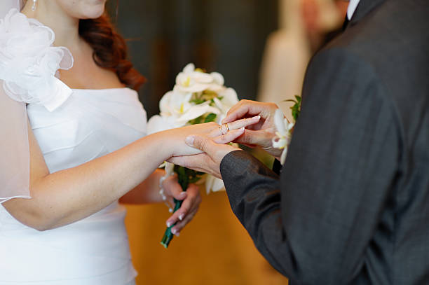 istock Groom putting the ring on bride's finger 451614825